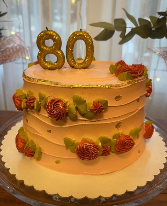 Bolo de aniversário de 80 anos em buttercream pêssego, com flores modeladas e borda dourada