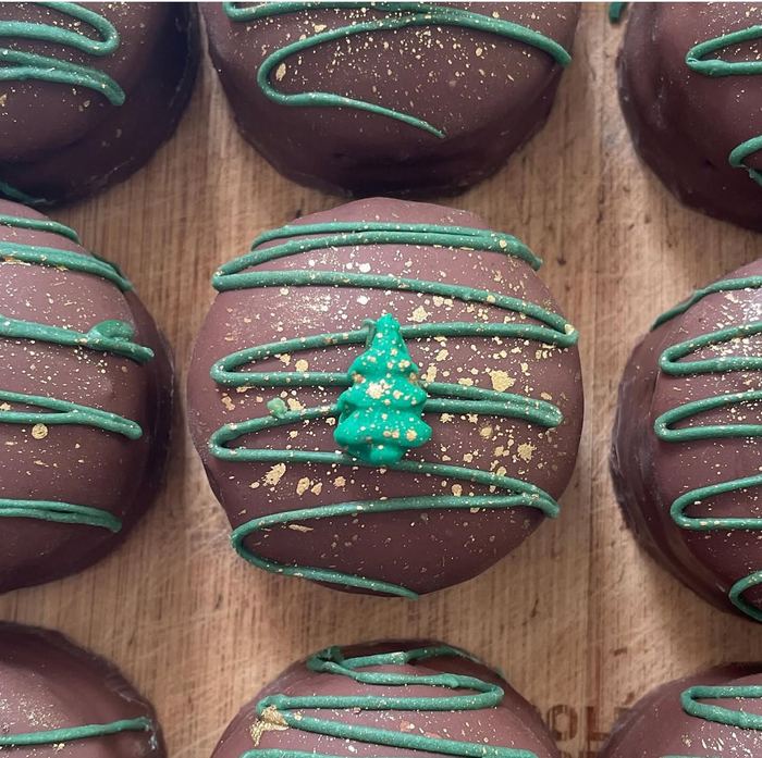 Bombons de Natal com fio verde, árvore de confeito e brilho dourado, sobre tábua de madeira