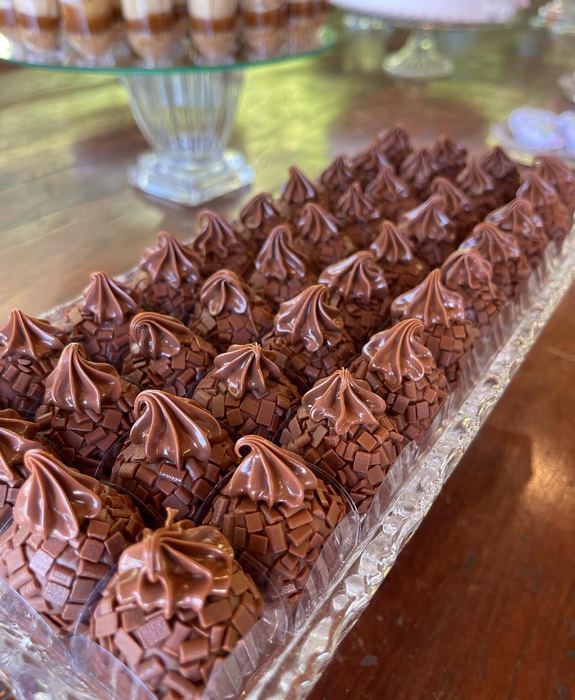 Brigadeiros com granulado belga finalizados com bico de brigadeiro no topo, em bandeja de cristal