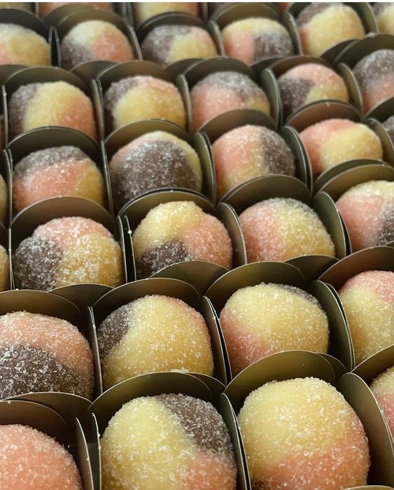 Doces bicolores passados no açúcar cristal, em forminhas douradas