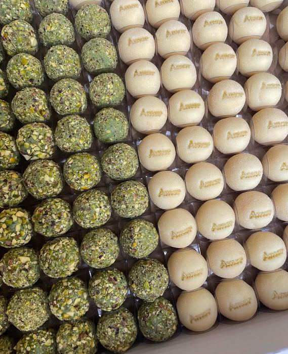 Doces de pistache ao lado de doces com a palavra Amor escrita em dourado à mão