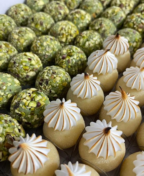 Doces de pistache ao lado de doces finalizados com merengue maçaricado