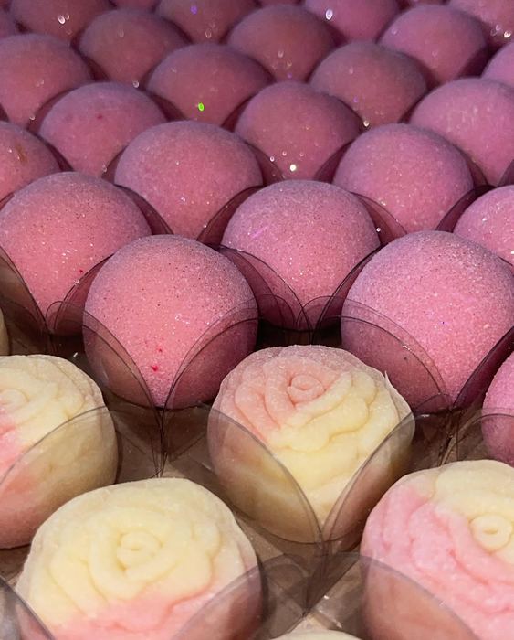Doces rosa com brilho comestível ao lado de doces modelados em formato de rosa bicolor